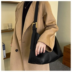 Detail of a black leather Hobo bag with wide shoulder strap and gold square buckle