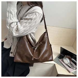 Detail view of large vintage brown hobo bag on wooden stairs with lifestyle accessories