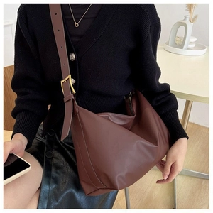 Close-up of brown soft leather tote bag with an adjustable strap and gold metal buckle
