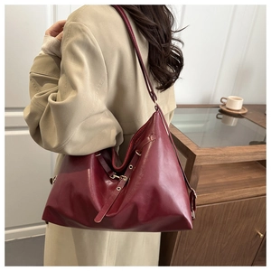 Side view of woman wearing a burgundy leather hobo bag over a beige trench coat