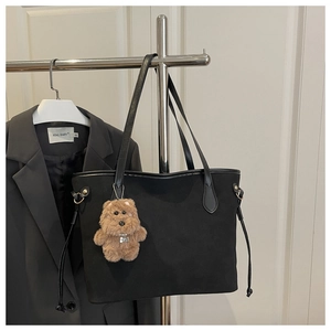 Détail du sac cabas en daim noir avec cordons de serrage et breloque d'ours marron