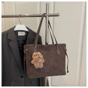 Détail d'un sac cabas en daim marron foncé avec un charmant pendentif ours en peluche