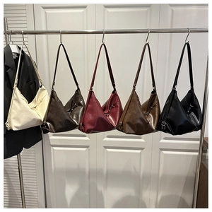 Row of vintage leather tote bags in beige, brown, and red on a sleek metal rack