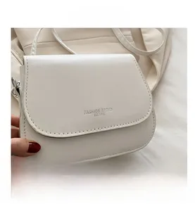 Detail of white saddle bag with Fashion Trend lettering and curved faux leather stitching