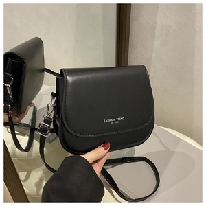 Detail of black matte saddle bag showing fashion logo and adjustable strap in hand