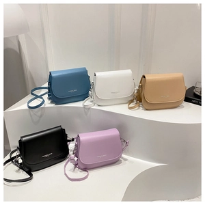 Five assorted minimalist saddle bags in blue, white, tan, black, and purple on a white stand