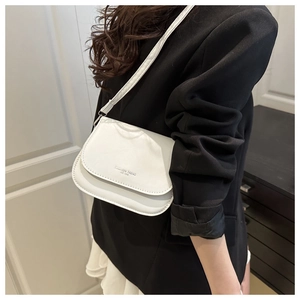 Close-up of white leather saddle bag with Fashion Trend text on black blazer