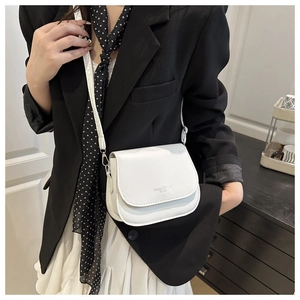 Close-up of a white leather crossbody bag featuring magnetic flap and silver logo print