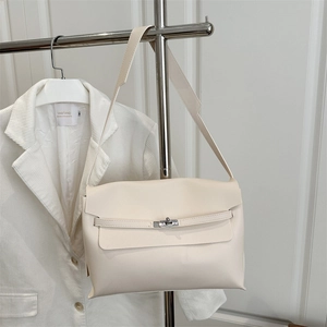 Elegant cream leather Kelly style shoulder bag with silver lock on a fashion display stand