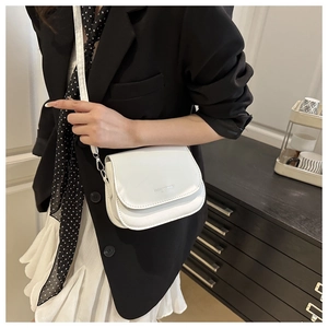 Detail of white saddle crossbody bag with fashion text on minimalist leather surface