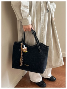 Black suede tote bag with white contrast stitching and a cute bear plush charm