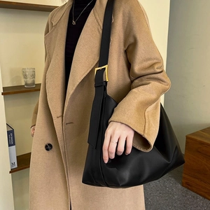 Minimalist black leather tote bag with wide shoulder strap and gold buckle for women