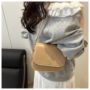 Close-up of light khaki flap crossbody bag with Fashion Trend print worn by a model