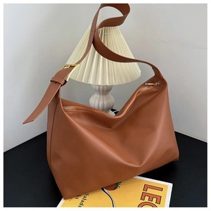 Minimalist brown hobo tote bag with gold buckle in a stylish indoor setting