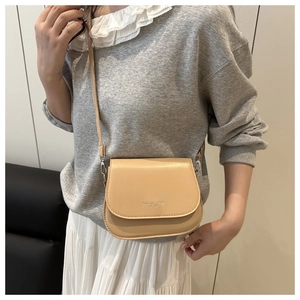 Detail of apricot semi-circular crossbody bag with FASHION TREND text and PU leather texture