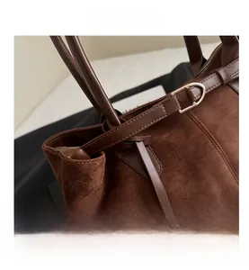 Detailed close-up of dark brown suede tote bag with golden D-ring buckle hardware