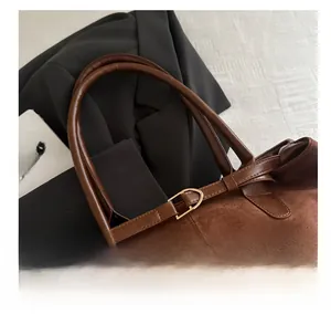 Close-up of vintage brown suede tote bag featuring metallic buckle and dual handles