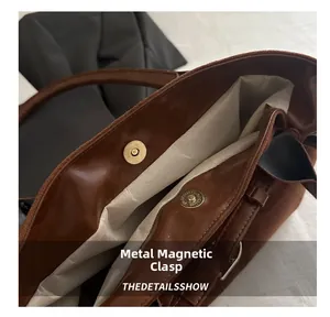 Detail of metal magnetic closure on a large capacity brown suede tote bag