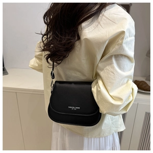 Close-up of black leather saddle bag with silver buckle and Fashion Trend text print