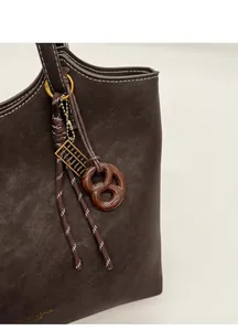 Détail du cabas en cuir grainé marron foncé avec ses charms bretzel et boulier