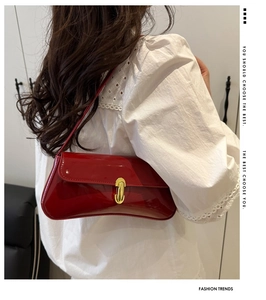 Detail of red patent leather shoulder bag with gold metal buckle on a model