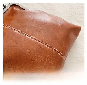 Détail d'un sac en cuir PU marron montrant les doubles surpiqûres et le fermoir métal