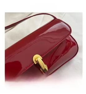 Close-up of red patent leather baguette bag with a premium golden metal lock buckle