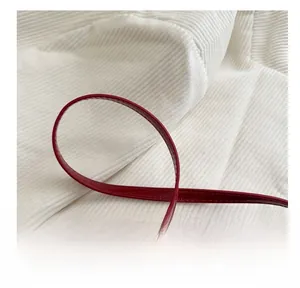 Detail of red glossy leather shoulder bag showing smooth cylindrical handle and stitching