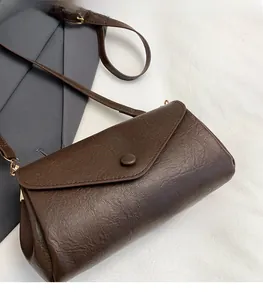 Close-up of brown vintage crossbody bag featuring textured lychee grain and envelope flap