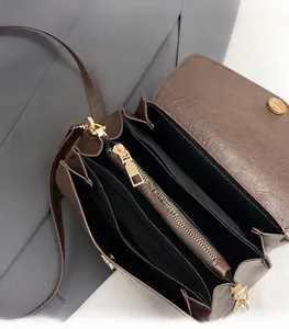 Detailed interior of brown leather crossbody bag with multiple compartments and gold zipper