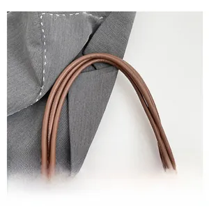 Detail of brown leather handles with gold metal buckles on a vintage tote bag