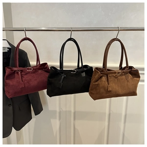 Three suede tote bags in burgundy, black, and caramel hanging for display