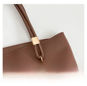 Detail of brown tote bag showing golden hardware buckle and fine leather stitching