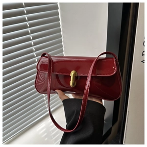 Close-up of shiny red patent leather shoulder bag with a gold twist lock and clasp