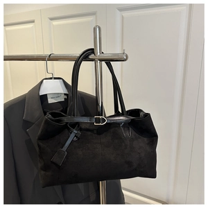 Detailed view of black suede tote bag featuring slim leather straps and metal buckle accent