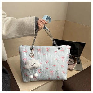 Detail of light blue floral bucket bag with chain strap and cute cloud charm in a cafe