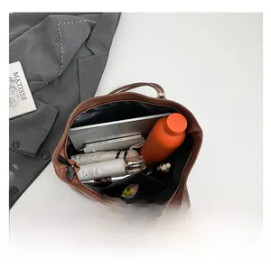 Spacious interior of brown faux leather tote bag holding a tablet, umbrella and makeup