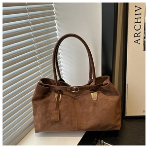 Close-up of brown faux suede tote bag featuring decorative buckles and thin shoulder straps