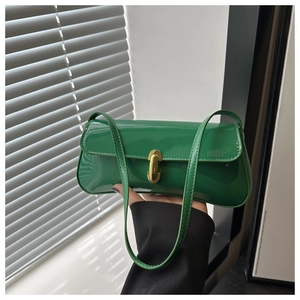 Detail of glossy green patent leather underarm bag with gold oval metal lock buckle
