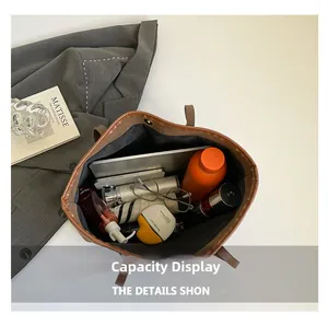 Gros plan d'un sac cabas marron montrant une grande capacité pour ordinateur et accessoires