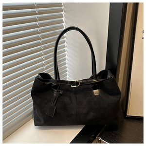 Detailed view of black suede tote bag with leather straps and metal buckle on window sill