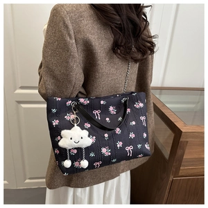 Detail of floral bucket bag with pink bow pattern, chain strap, and cloud charm