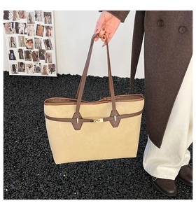 Détail de la sangle en cuir marron et du fermoir doré sur le sac fourre-tout en daim