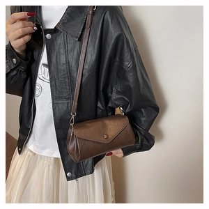 Close-up of vintage brown leather crossbody bag with envelope flap and button detail