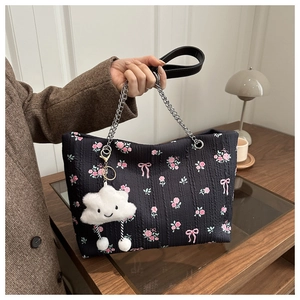 Detail of floral bucket bag with pink roses, silver chain strap, and plush cloud charm