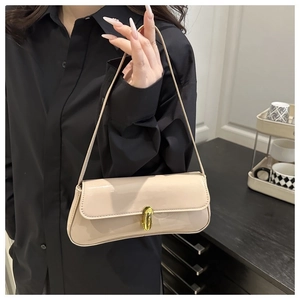 Close-up of cream patent leather underarm bag with gold twist lock on black shirt