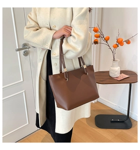 Brown minimalist tote bag detail with slim handles and golden metal ring connectors