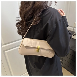 Detail of a creamy white patent leather baguette bag with a gold twist lock buckle