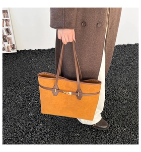 Détail du sac cabas en daim orange avec ses anses en cuir marron et boucle métallique