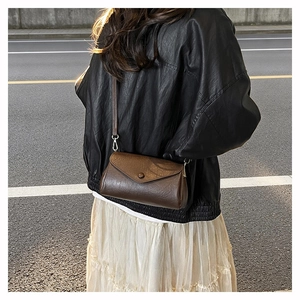 Close-up of a vintage dark brown leather crossbody bag with adjustable shoulder strap